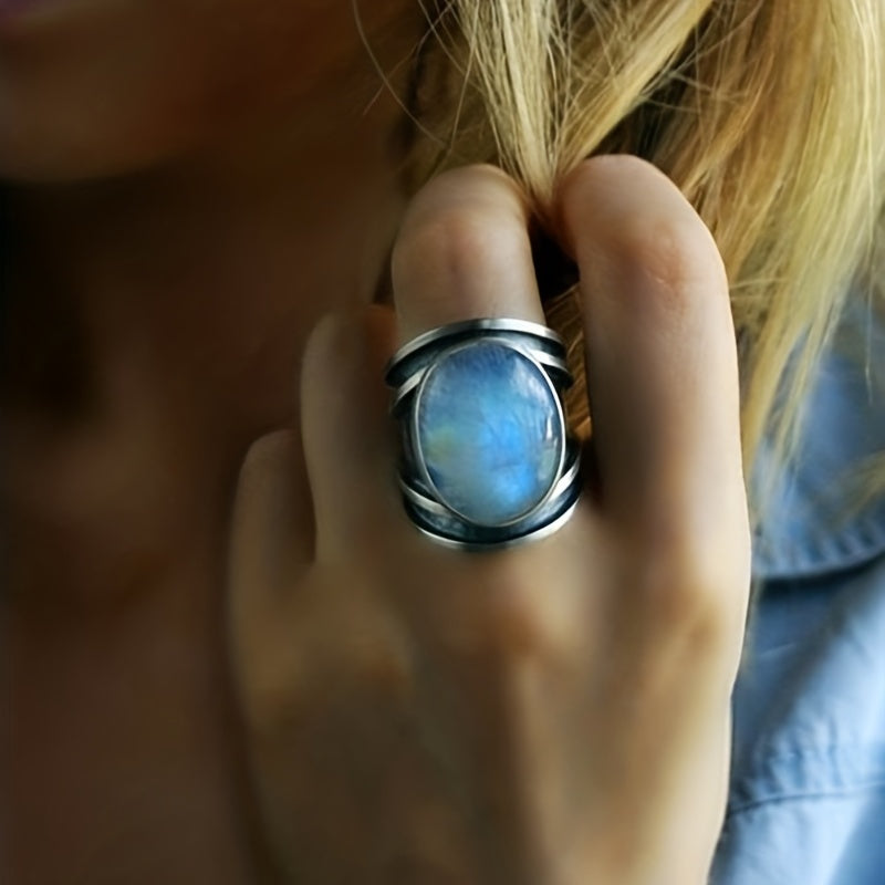 Large blue oval statement ring with open silver-tone side details worn on a hand.