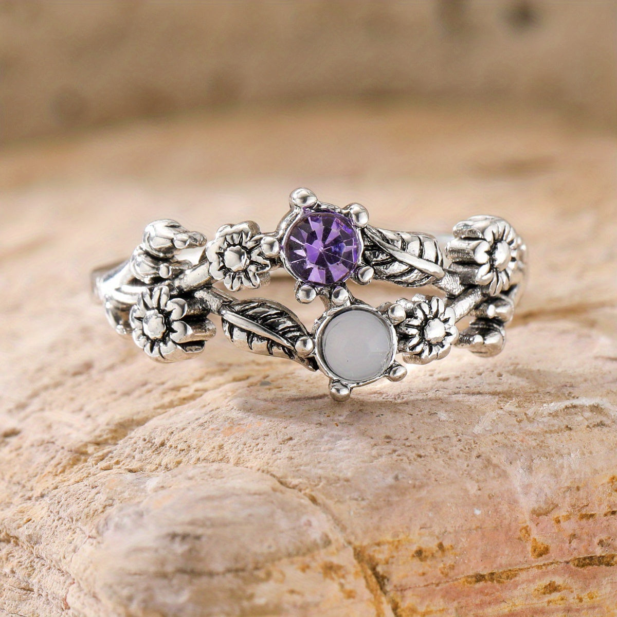 Silver-tone floral ring with purple and white accents, raised flowers, and curling leaf details.