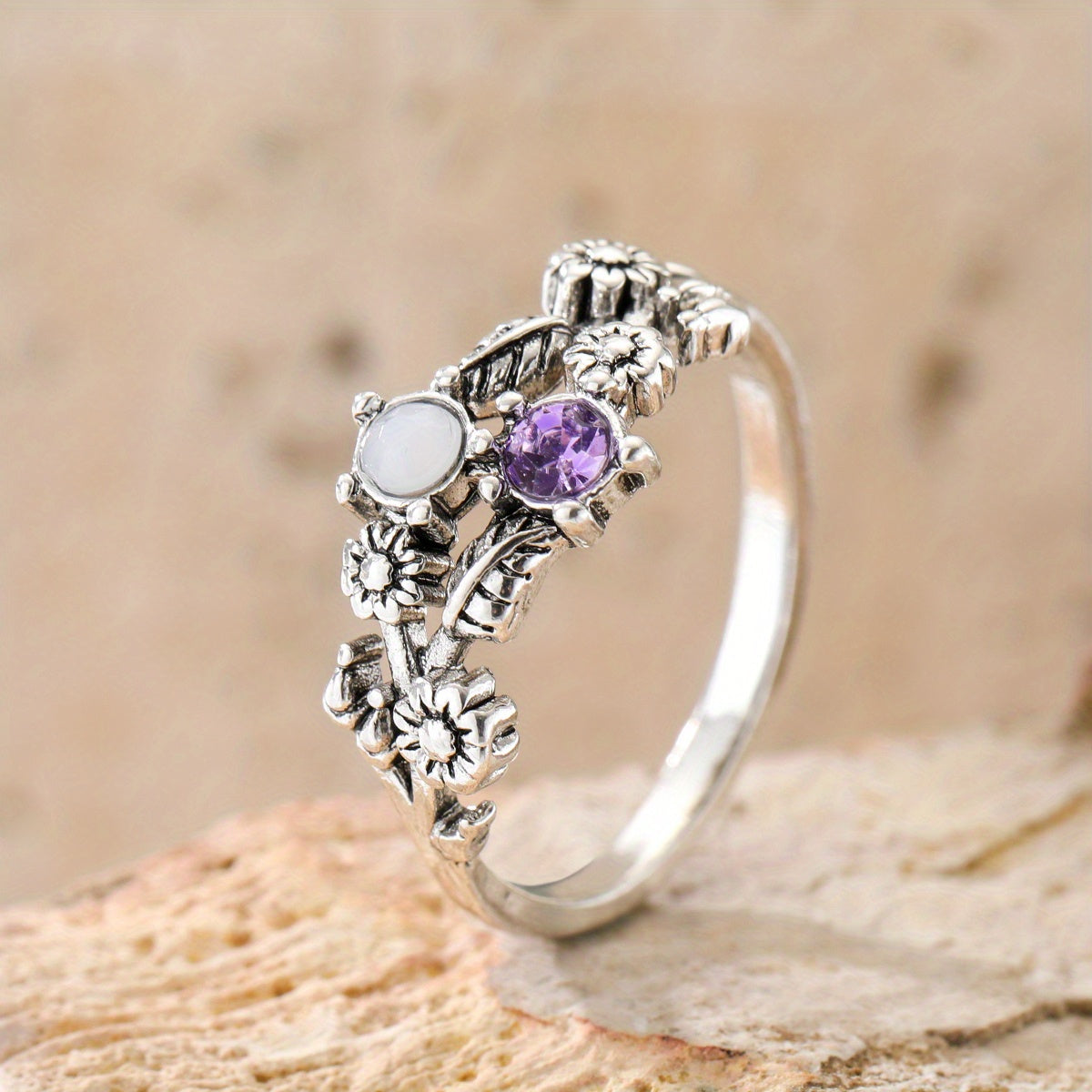 Silver-tone floral ring with purple and white accents, raised flowers, and curling leaf details.