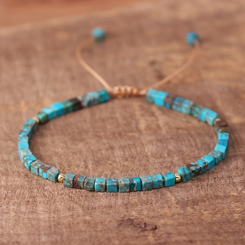 Turquoise-colored square bead bracelet with dark markings, small gold-tone spacers, and an adjustable tan cord.