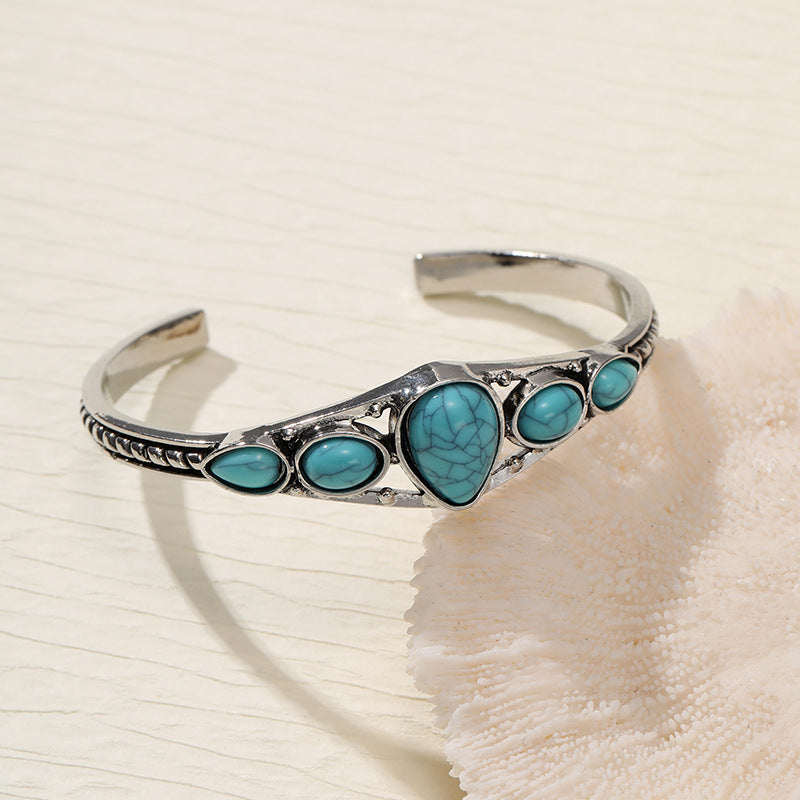 Silver-tone open cuff with a turquoise-colored central teardrop and four smaller side accents.