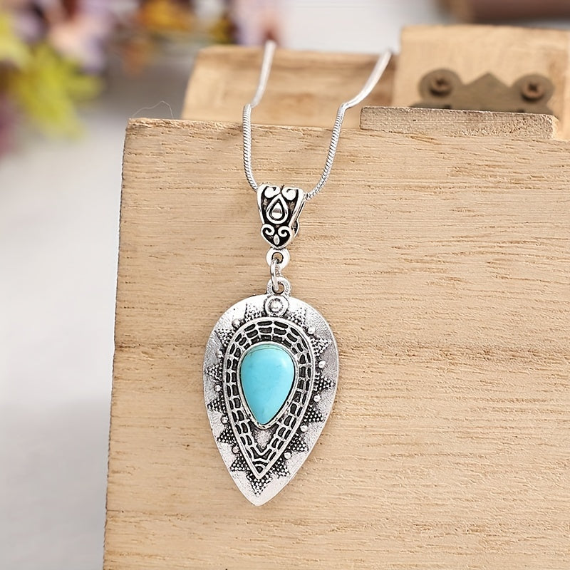 Turquoise-colored teardrop center in a large ornate silver-tone pendant on a fine matching chain.