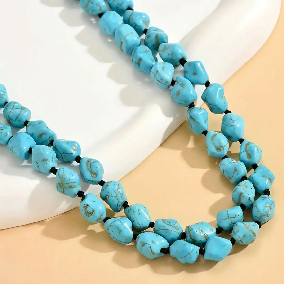 Close-up of two strands of irregular turquoise-colored beads with small dark spacers.