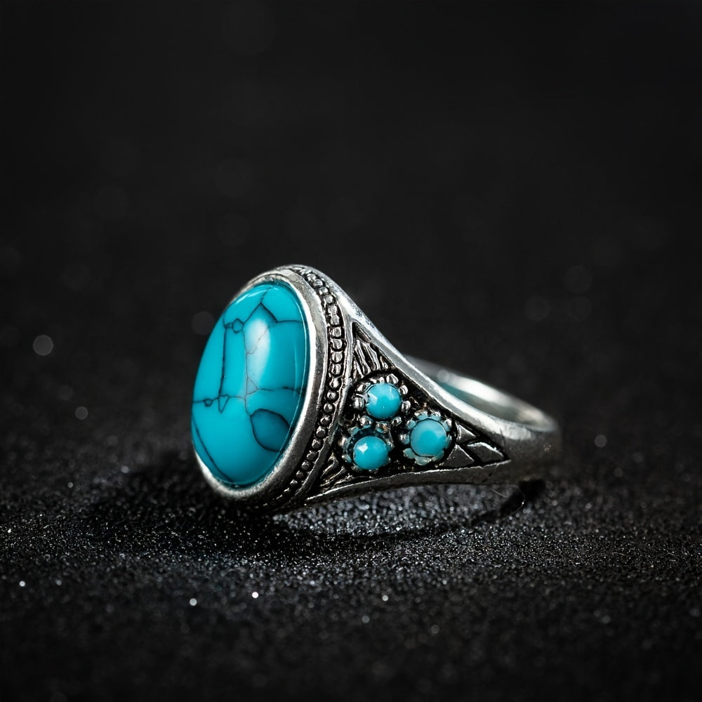 Silver-tone ring with a turquoise-colored oval center, dark veining, and small round blue side accents.