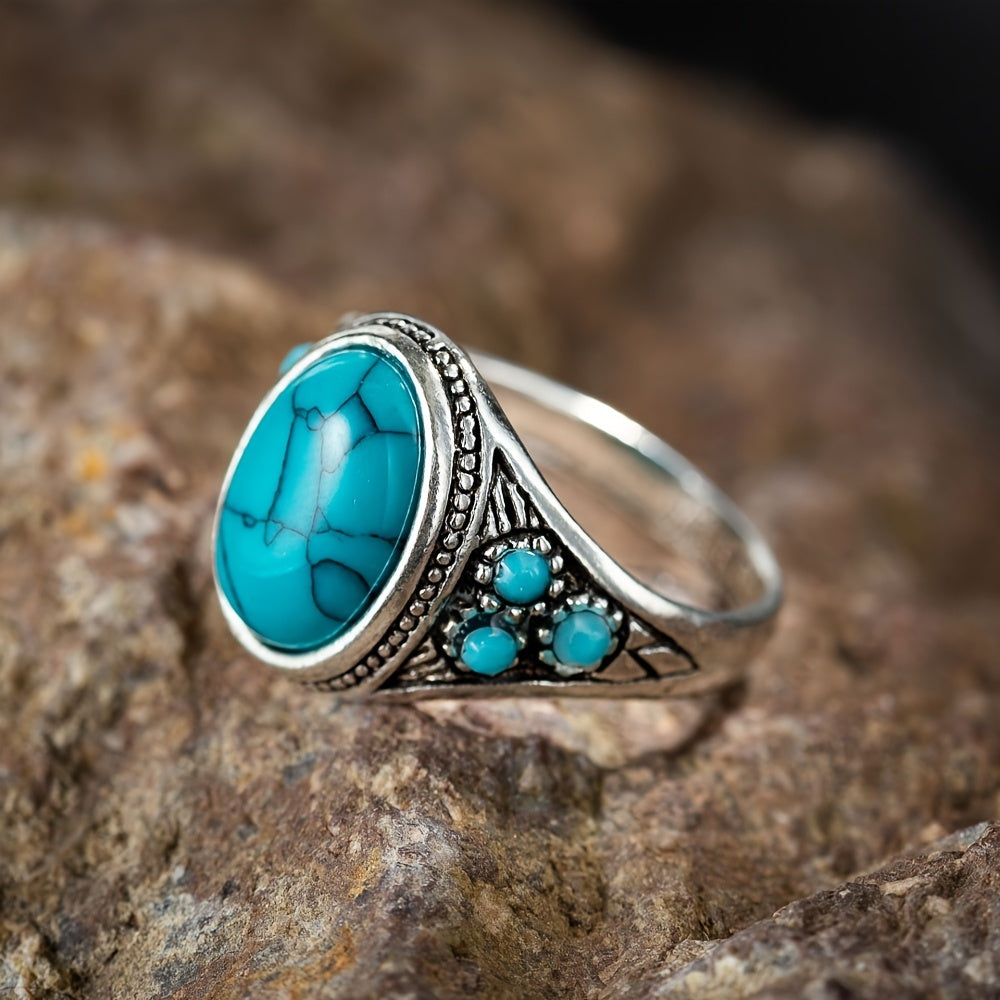 Silver-tone ring with a turquoise-colored oval center, dark veining, and small round blue side accents.